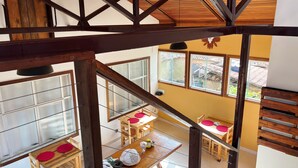 A high-ceilinged room with wooden beams, large windows, and a dining area with a table and chairs. - Pousada Vista de Lavras (Ouro Preto)