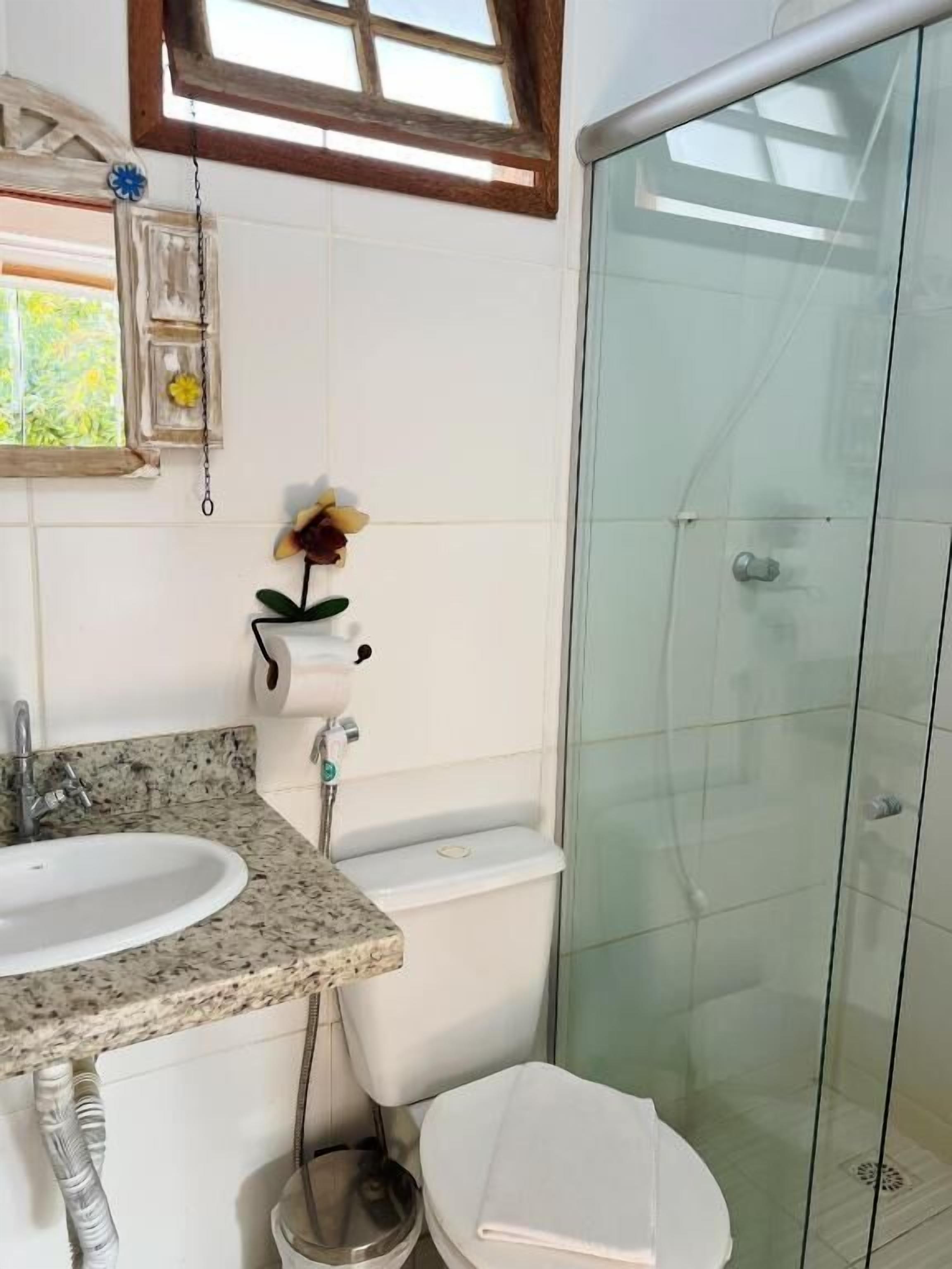 A bathroom with a sink, toilet, and glass shower enclosure.
