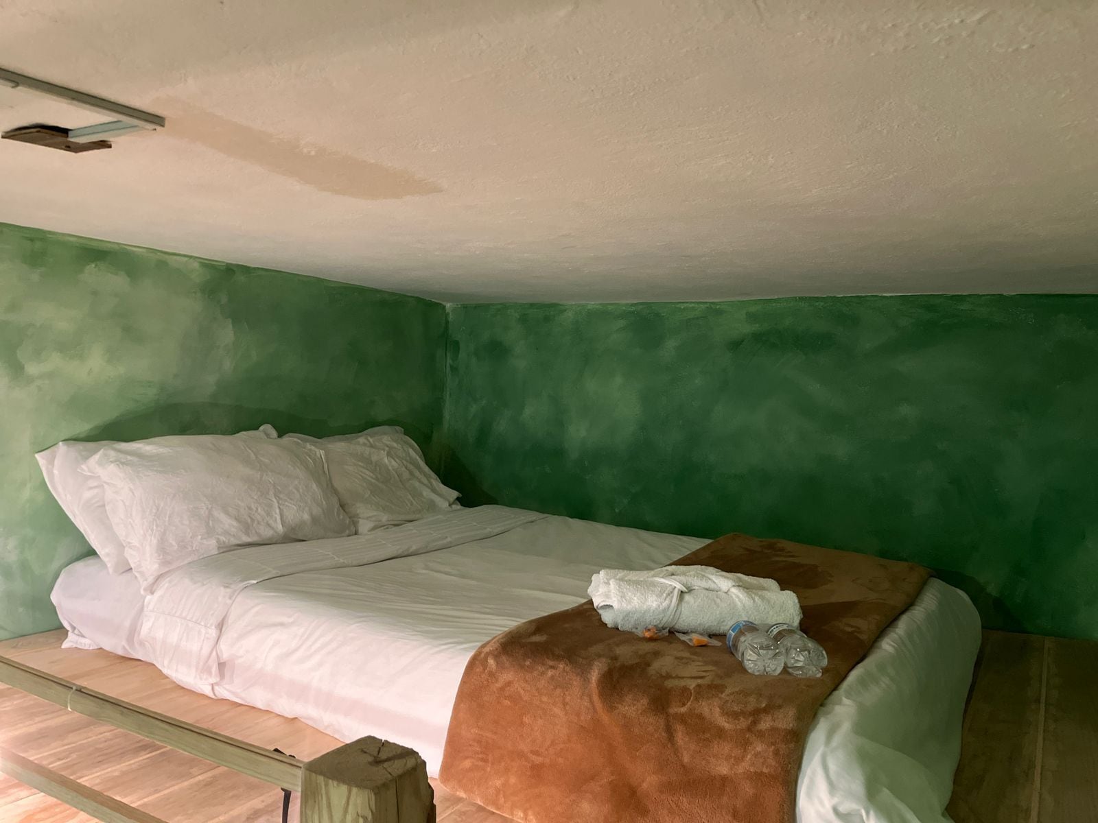 A room with a bed, green walls, and a wooden floor.