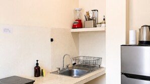 A compact kitchen with a sink, a microwave, a stainless steel refrigerator, a built-in induction cooktop, and a small countertop with a blender and other items. - Casa Maakja (Ixmiquilpan)