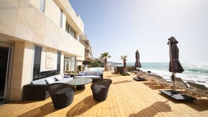 A wooden deck with outdoor seating, a pool, and a view of the sea.