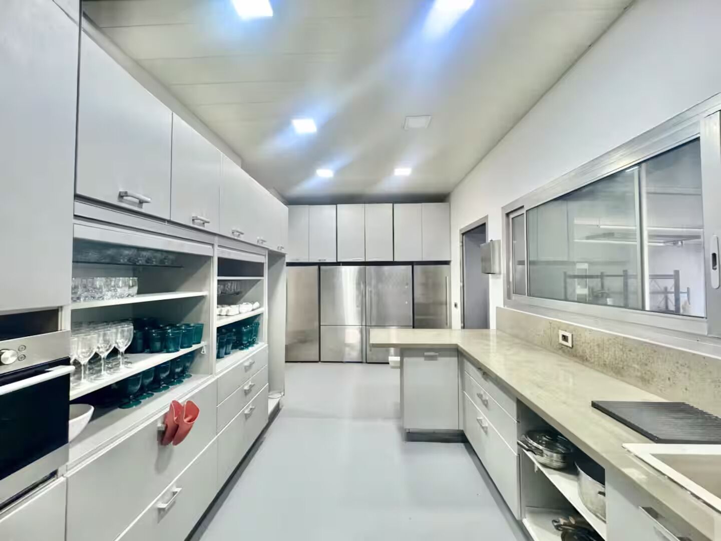 Una cucina moderna con elettrodomestici in acciaio inossidabile, mobili bianchi e un'ampia finestra.