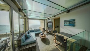 A modern interior with a glass ceiling, a sofa set, a dining table, and a TV.