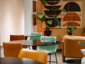 Ein modernes Interieur mit runden Tischen und Stühlen, einem Blumentopf und einer dekorativen Wandverkleidung.