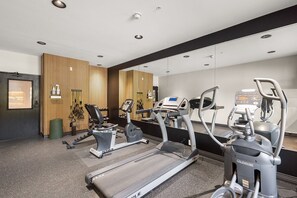 Un gimnasio con cintas de correr, elípticas y máquinas de pesas.