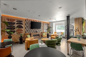 Un área de estar moderna con sofás de cuero, una chimenea, un televisor de pantalla plana y un comedor con una mesa y sillas de madera.