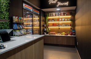 A snack bar with a neon sign, refrigerated display, and shelves stocked with snacks. - Boutique King Suite — On-Site Dog Park, Bike Storage, Espresso Bar (Bentonville)
