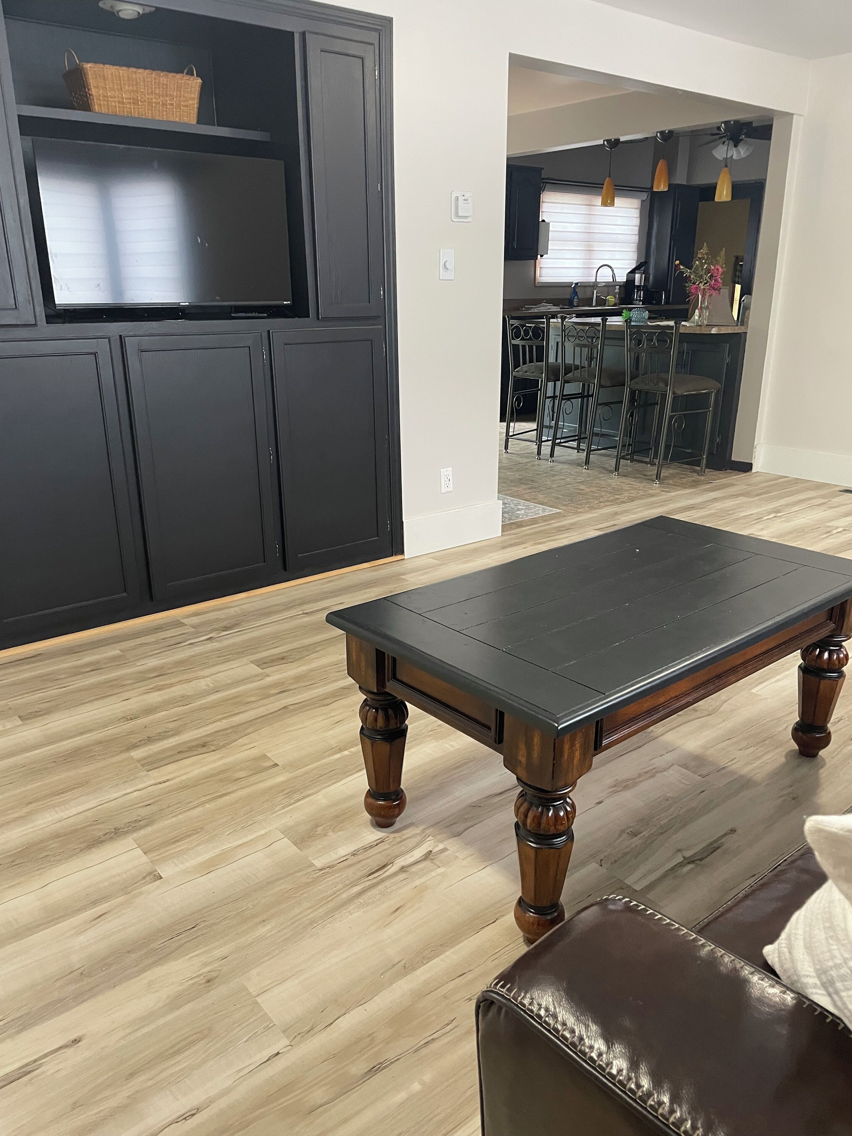 Une pièce dotée d’un plancher en bois, d’un canapé en cuir marron foncé et d’une table basse en bois foncé.