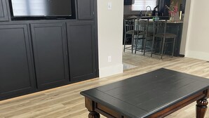 Una habitación con piso de madera, un sofá de cuero marrón oscuro y una mesa de centro de madera oscura.