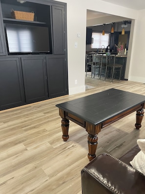 A room with a wooden floor, a dark brown leather sofa, and a dark wooden coffee table.
