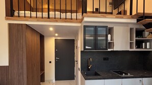 A modern kitchen with a marble floor, a built-in oven, and a black countertop. - Premium Heritage Loft on Piotrkowska (Łódź)