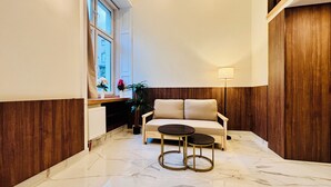A modern interior with a marble floor, a sofa, a small round table, and a lamp. - Premium Heritage Loft on Piotrkowska (Łódź)