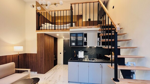 A modern interior with a kitchen, dining area, and a staircase. - Premium Heritage Loft on Piotrkowska (Łódź)