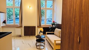 A modern living room with a marble floor, a sofa, a small round table, and a wooden wardrobe. - Premium Heritage Loft on Piotrkowska (Łódź)