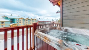 Uma banheira de hidromassagem em um deck de madeira com vista para edifícios ao fundo.