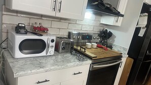 A kitchen with white cabinets, a microwave, a toaster, a cutting board, and a refrigerator. - 3/2 house in Statesboro with nearby GA Southern and Savannah (Statesboro)