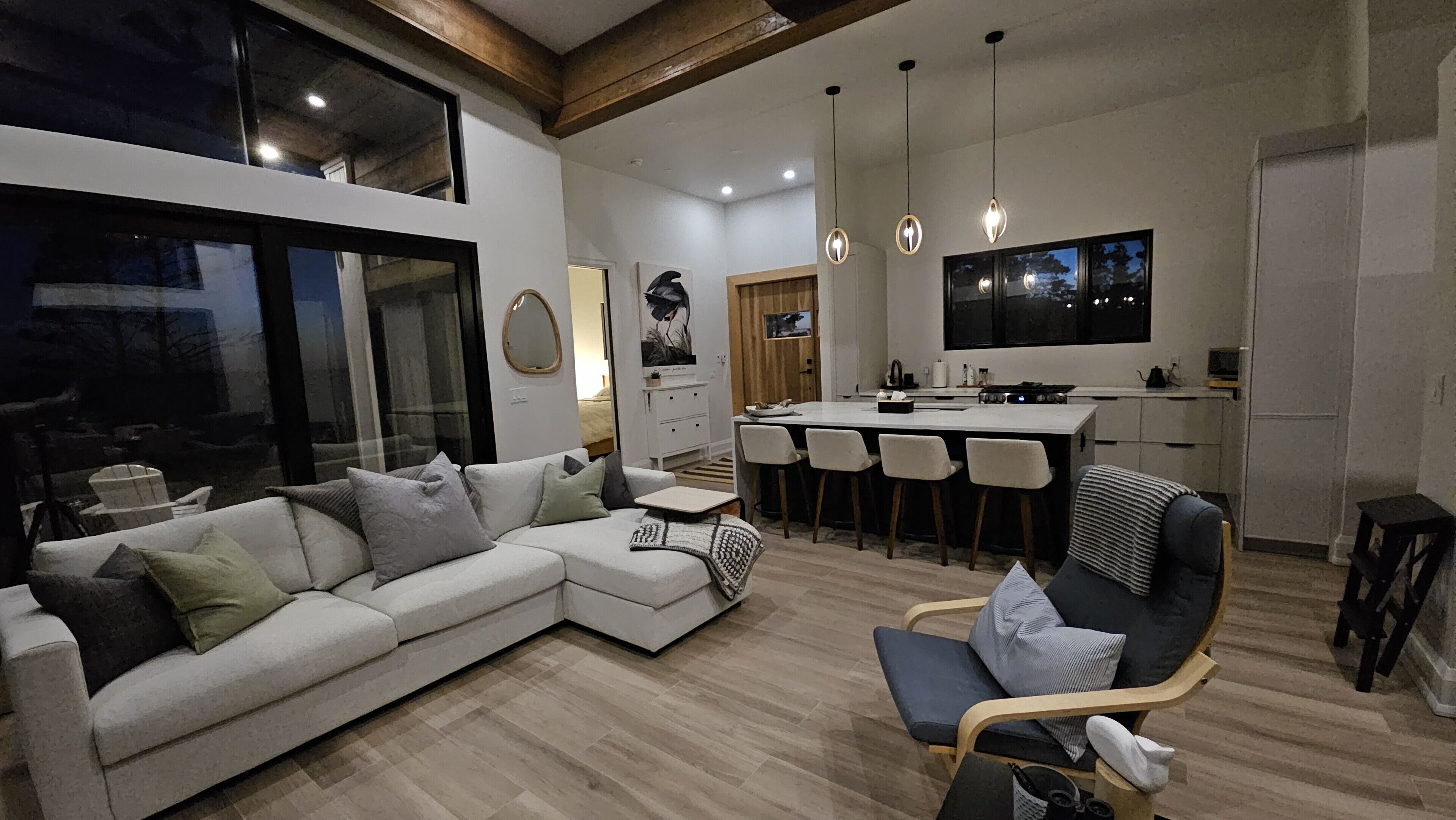 Uma sala de estar moderna com sofá, área de jantar com cadeiras, cozinha com TV e janelas amplas.