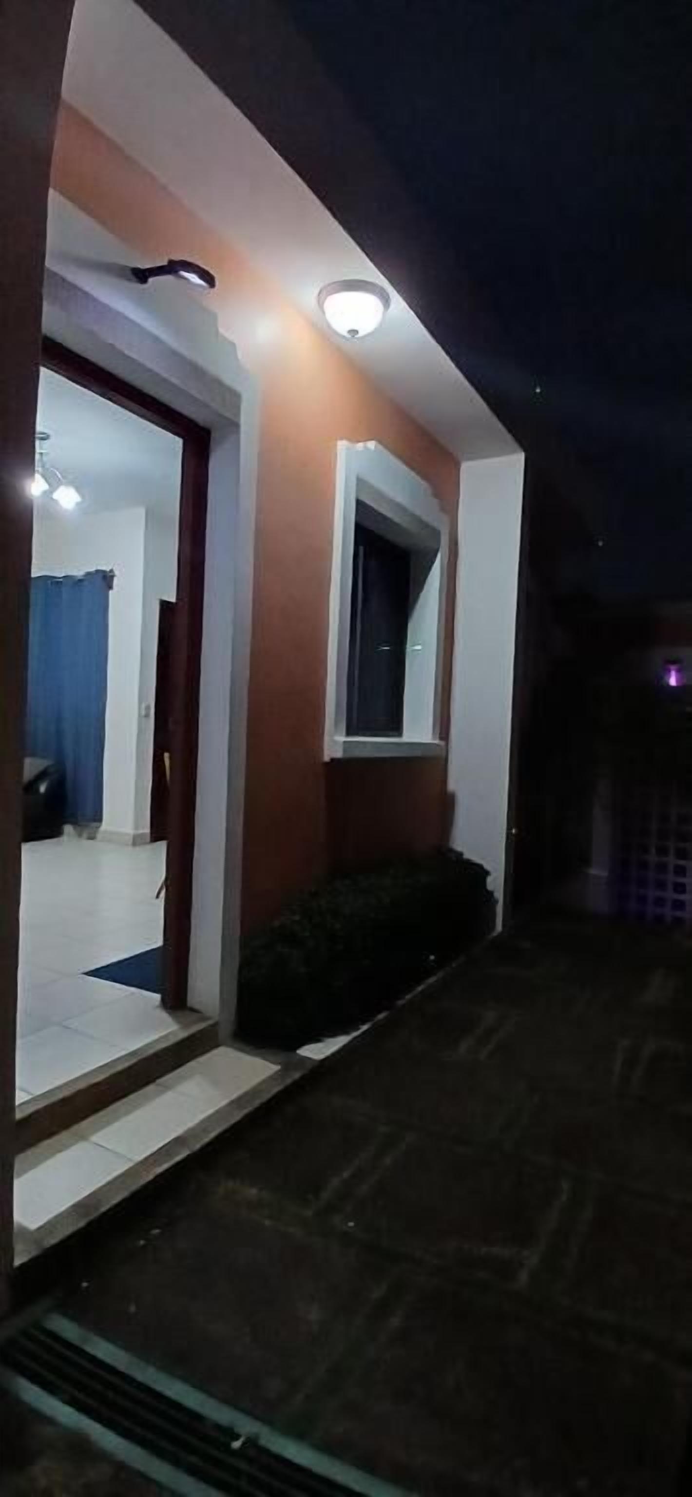 Een modern huis met een goed verlichte entree, een zichtbare deur en een raam.
