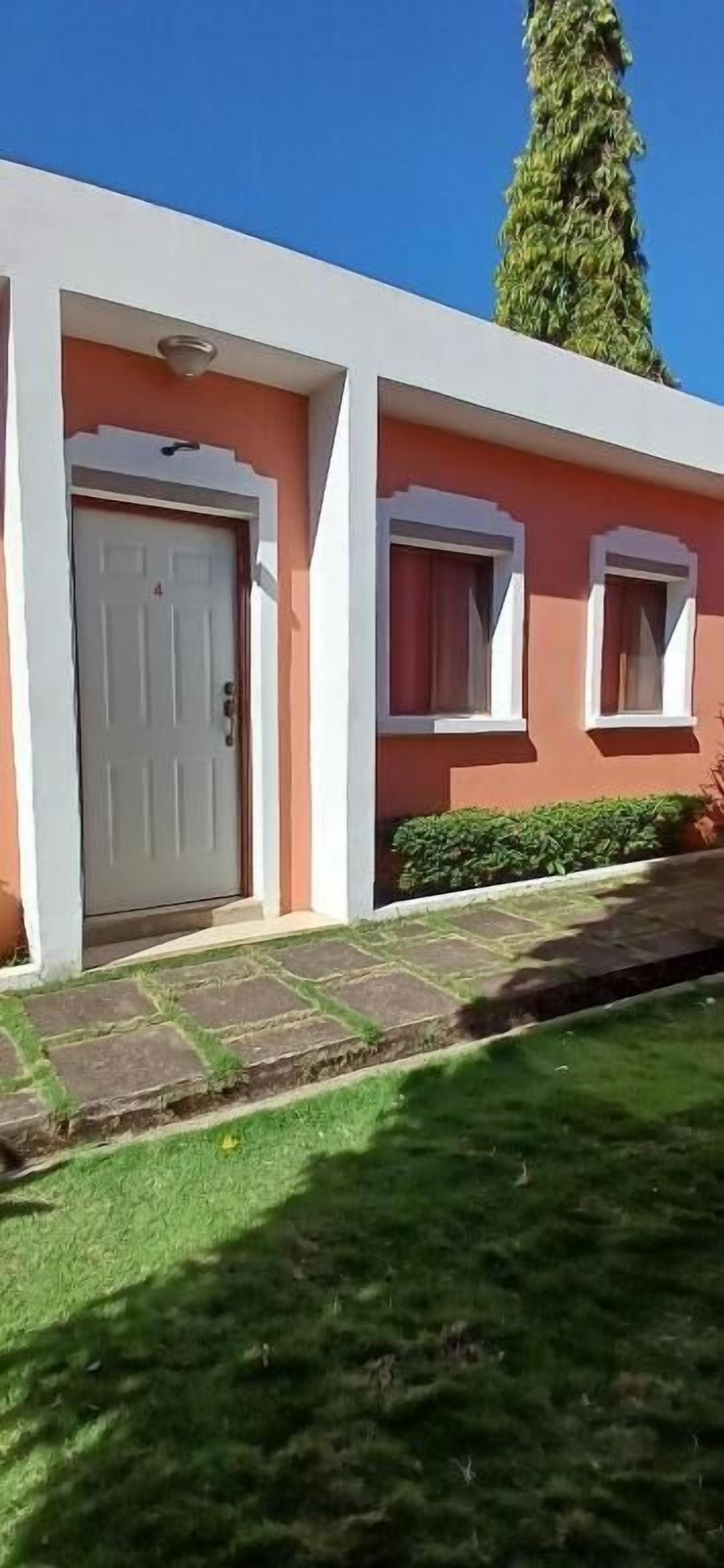 A building with a white door, a window, and a small garden area.