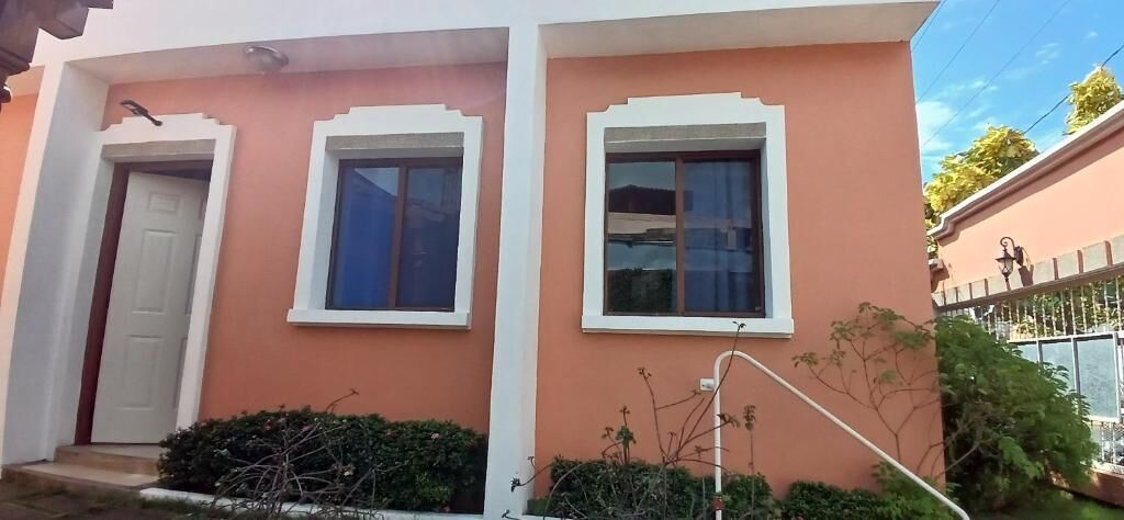 A building with two windows, a door, and a small garden area.