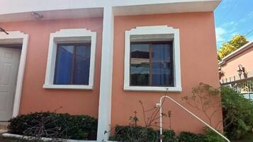 A building with two windows, a door, and a small garden area.