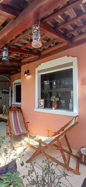 A wooden ceiling with exposed beams, a large window with a white frame, and two wooden chairs.
