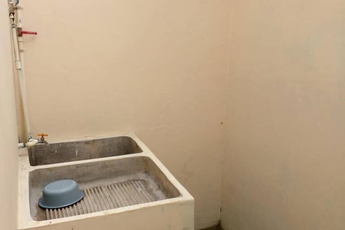 A small, white bathroom with a single sink, a blue basin, and a visible pipe.
