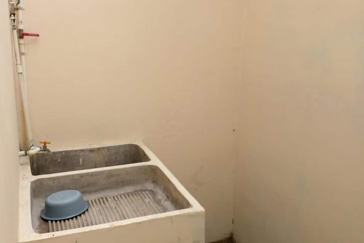 A small, white bathroom with a single sink, a blue basin, and a visible pipe.