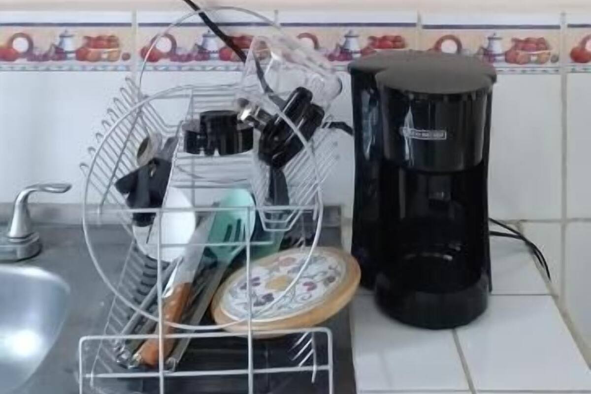 A kitchen with a shelf holding glassware and a coffee maker on the counter.