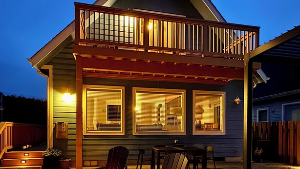 Una casa con terraza, mobiliario exterior y una chimenea.