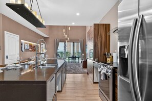 A modern kitchen with a central island, stainless steel appliances, and a view to the outside. - Spacious 3BR/3.5BA Home Near Disney in Kissimmee (Kissimmee)