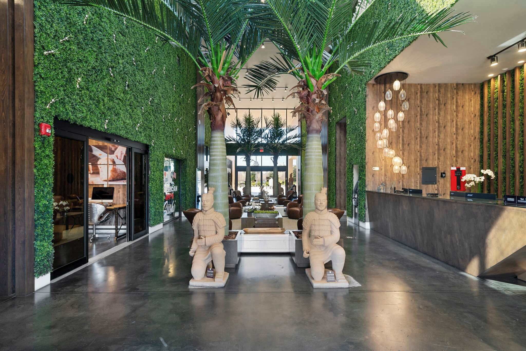 A lobby with a green wall, two statues, a reception desk, and a seating area.