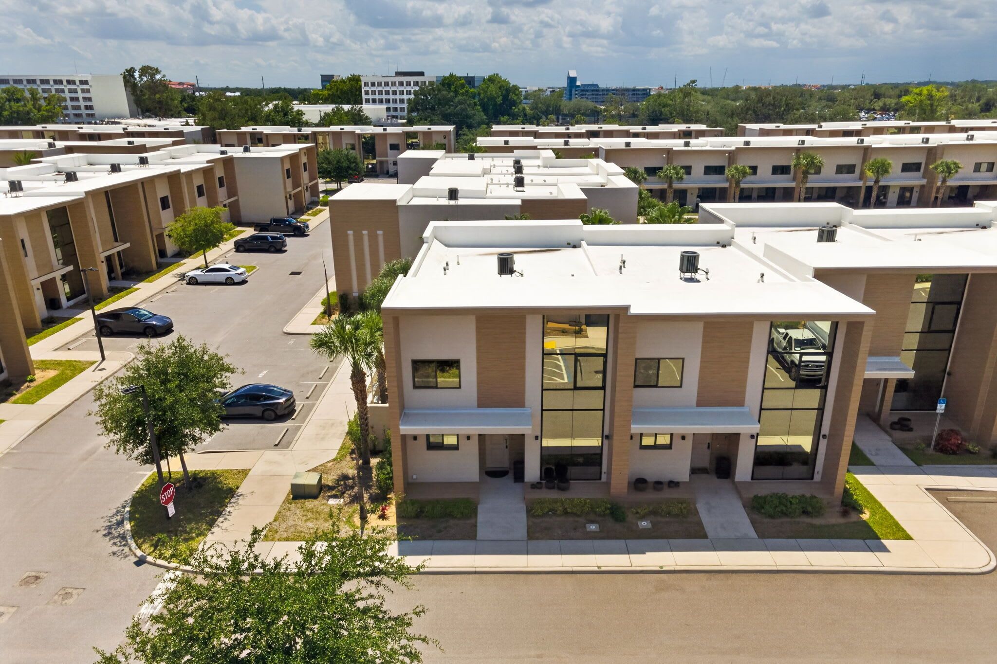 A modern apartment complex with multiple buildings, a parking lot, and a clear sky.