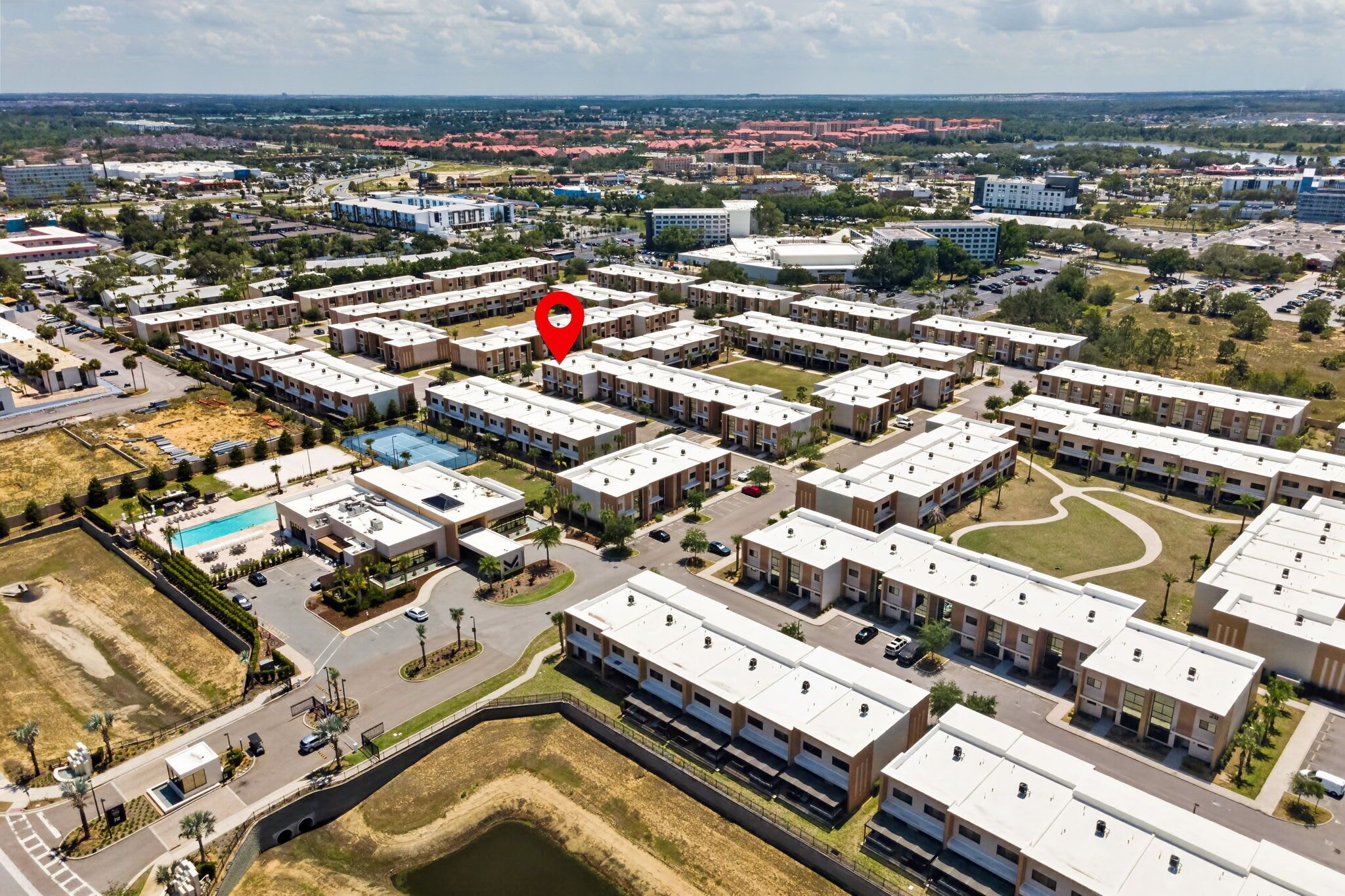 Vue aérienne d’un quartier résidentiel comprenant plusieurs immeubles d’appartements, une piscine et un parking.