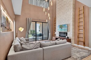 A modern living room with a sectional sofa, a TV, and a fireplace. - Spacious 3BR/3.5BA Home Near Disney in Kissimmee (Kissimmee)