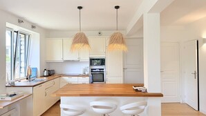 Eine moderne Küche mit weißen Schränken, einer Holz Arbeitsplatte und zwei Pendelleuchten.