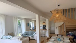 Ein moderner Wohnbereich mit einer Couch, einem Esstisch für vier Personen und einer Küche im Hintergrund.