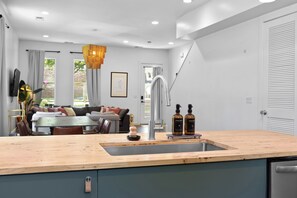 A modern kitchen with a wooden countertop, stainless steel sink, and a dining area with a sofa and table. - Side by Side Duplex-8 Min to Broadway-Fenced Backyard with Plunge Pool-10 Beds (Nashville)