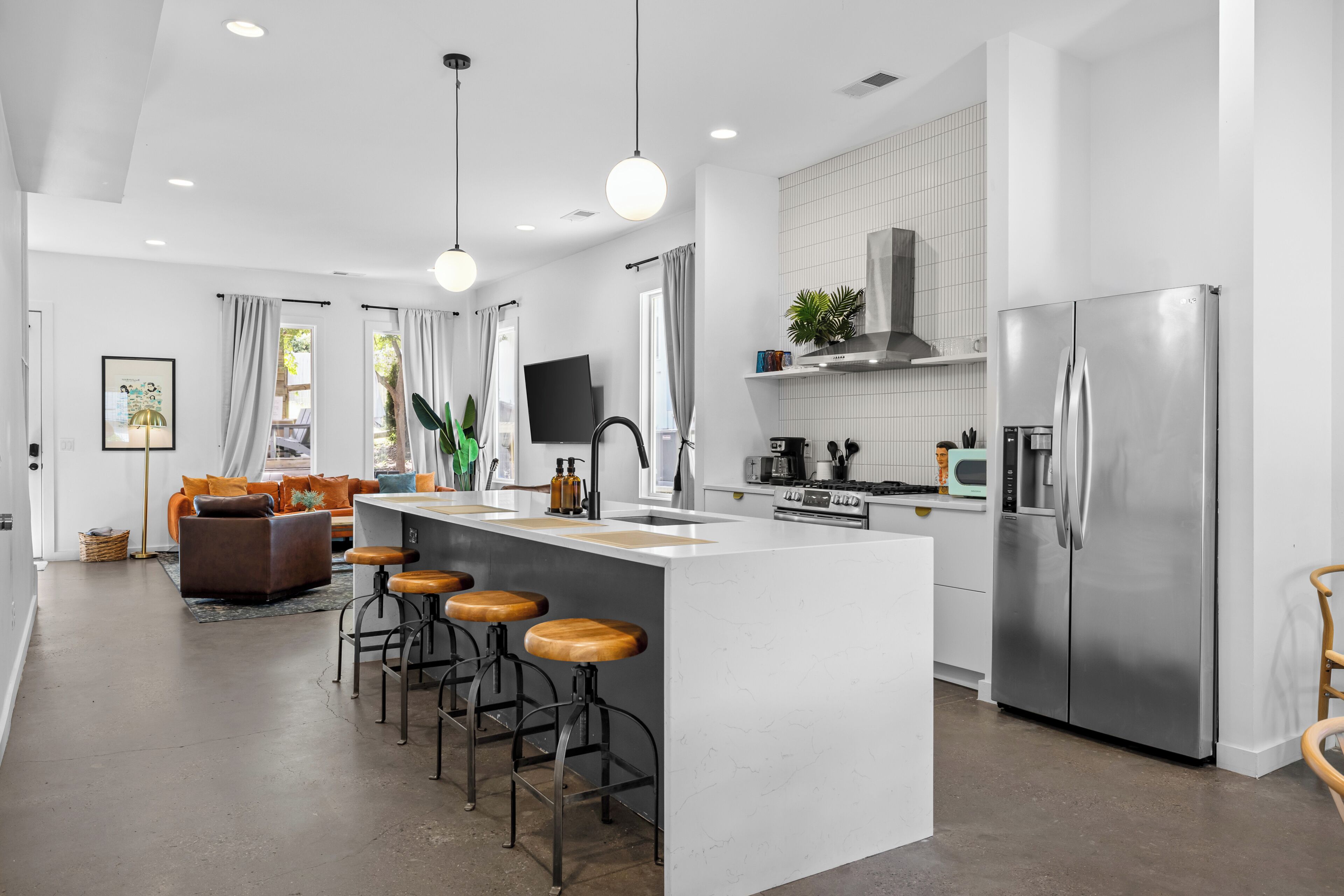 A modern kitchen with a central island, stainless steel appliances, and a dining area with bar stools.