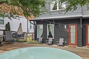 Ein Wohnhaus mit Swimmingpool, Liegestühlen und einer Fassade in Dunkel gehaltenen Farben sowie einer roten Tür.