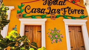 Fachada de un edificio con el letrero 'Nostal Casa las Flores' y dos puertas de madera.