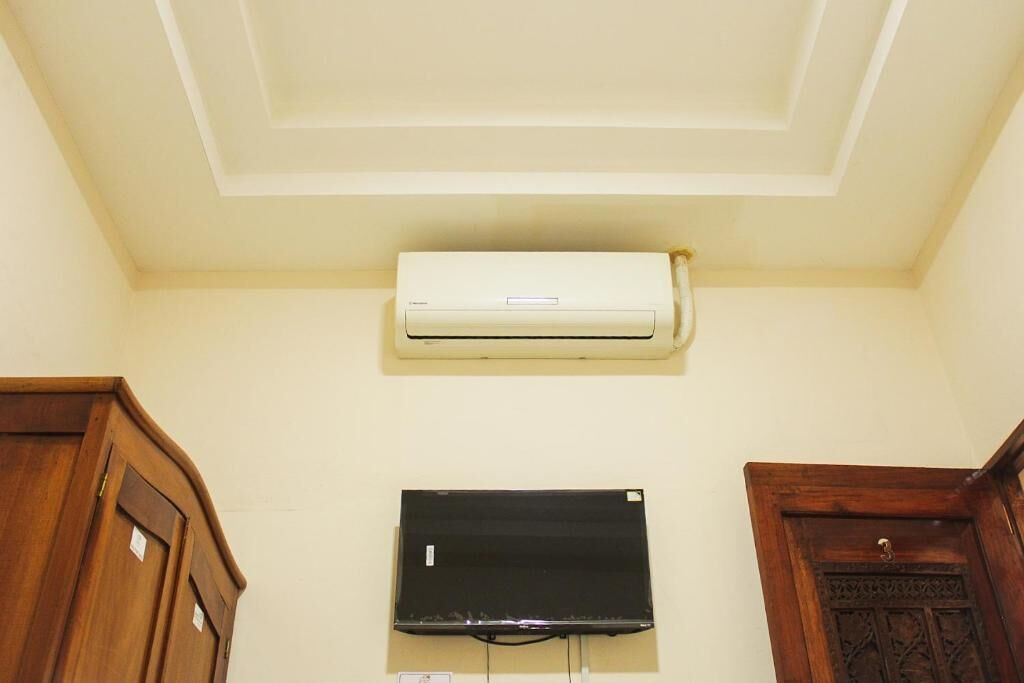 A room with a ceiling fan, a mounted air conditioner, and a wall-mounted television.