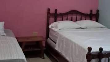 Un dormitorio con dos camas, una pared rosa y un cabecero de madera.