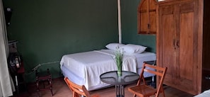 A room with two beds, a small round table, a chair, and a wooden wardrobe.