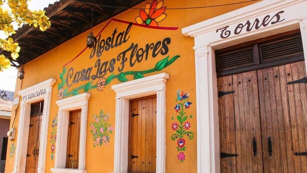 A building with a sign reading 'Mestal Casa las Flores' and a wooden door labeled 'Torres.' - Hostal Casa Las Flores (Masaya)