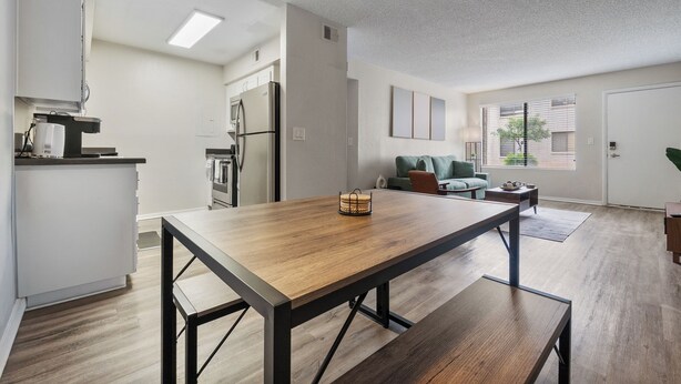Una cocina moderna con una mesa y banco de madera, un refrigerador y un área de comedor con un sofá y una mesa de centro.