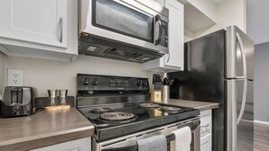 Una cocina equipada con estufa, microondas y refrigerador.