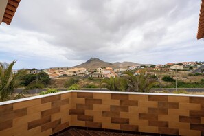 Ein Balkon mit Blick auf eine Wohngegend und ein Berg.