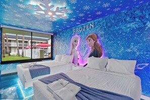 A hotel room with a large bed, a view of the outside, and a wall mural with the word 'FROZEN'. - Frozen-Themed Studio with Pool (Kissimmee)