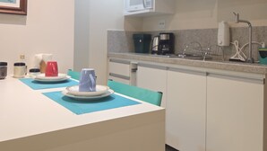 Eine moderne Küche mit weißen Schränken, einer Mikrowelle, einer Kaffeemaschine und einem Spülbecken.
